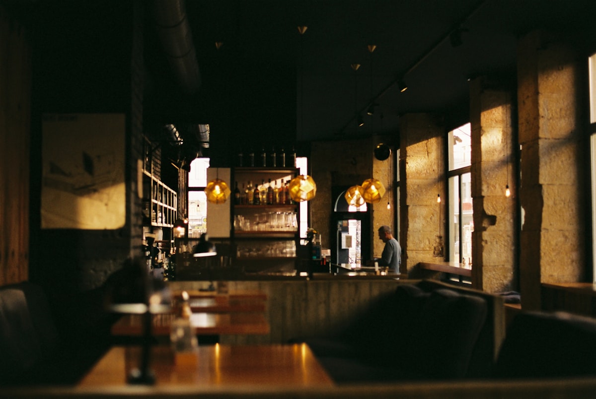Warm, dimly lit dining room at Amber and Oak with a glowing bar in the background